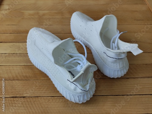 White fabric sneakers on the wooden background