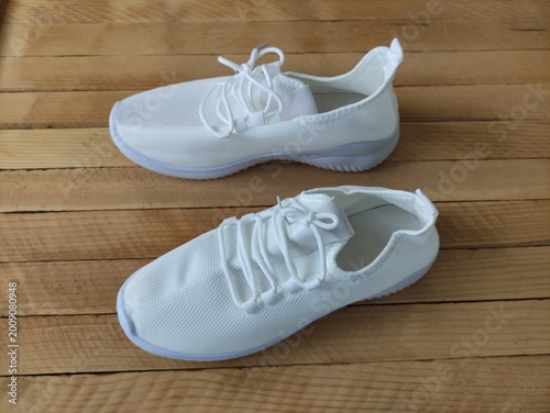 White fabric sneakers on the wooden background