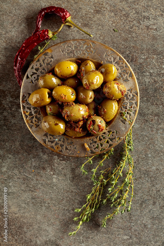 Photography Spicy green olives in olive oil on a old stone table.