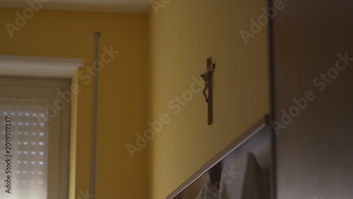 Quadro su tela Wooden Crucifix Hanging on Yellow Wall in Home Interior Above Door Frame with Wa