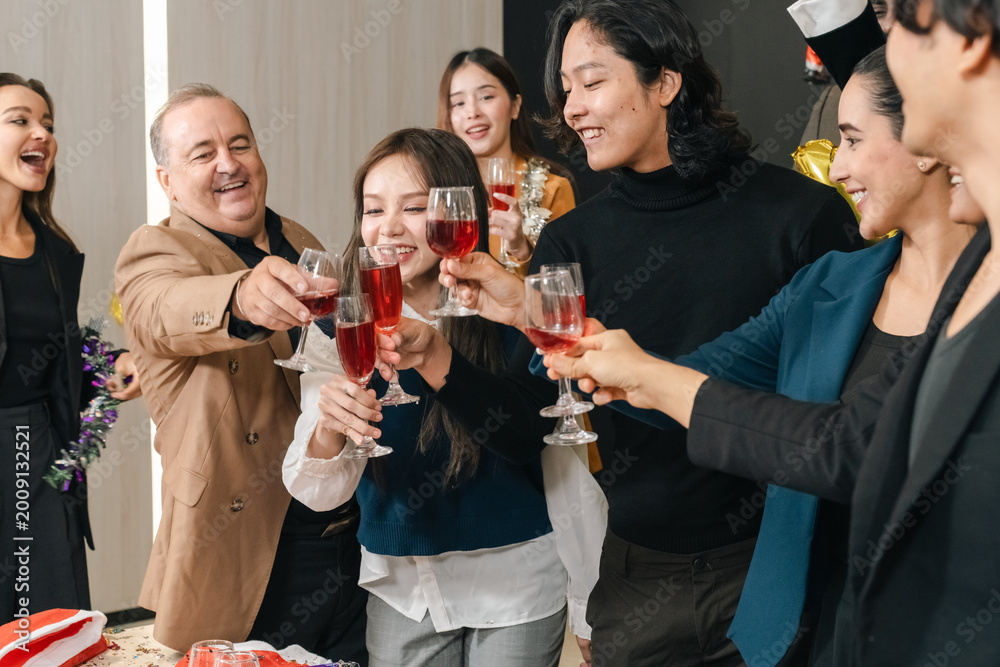 Fototapeta premium Celebration group of diverse adult friends toasting with wine glass in indoor party, smiling social gathering with happy people