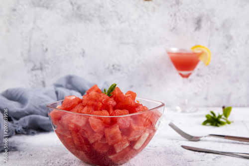 Fresh diced watermelon bowl with summer drink on light background