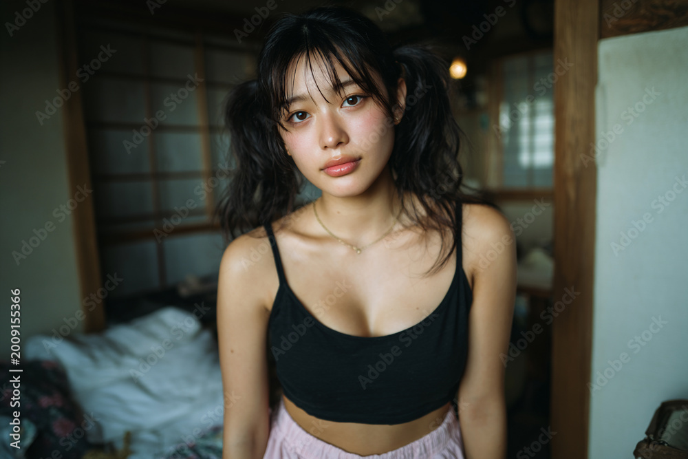 Fototapeta premium serene east asian woman in morning light, young asian woman relaxing in traditional japanese room with soft sunlight, calm portrait of woman with ponytails in airy tatami bedroom