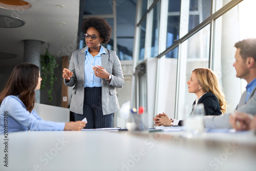 фотографія Black CEO discussing work with her team in an office boardroom.