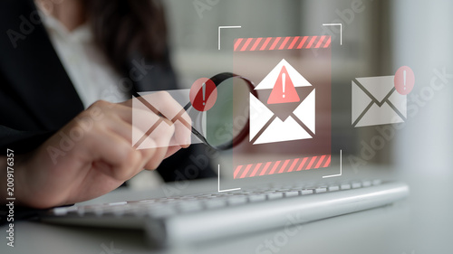 Photos A focused businessperson examines email notifications highlighting alerts and warnings, emphasizing the importance of cybersecurity in a modern office setting