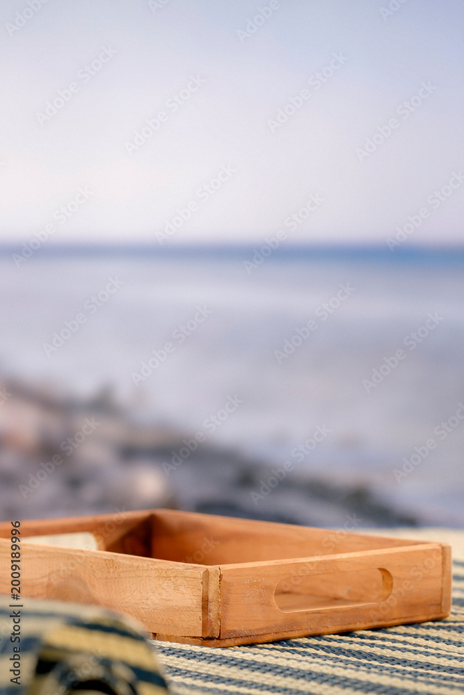 Fototapeta premium Minimal summer composition featuring clean sandy beach with empty copy space for product placement. Rocky coastline meets the sea under bright blue sky, creating natural and scenic atmosphere.