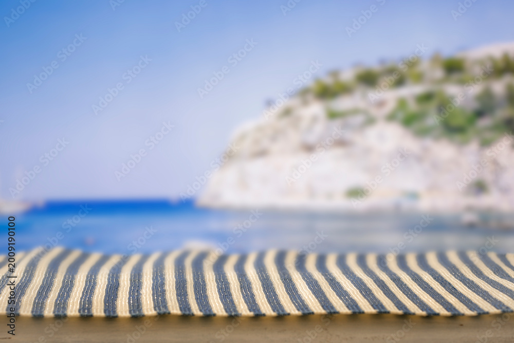 Obraz premium Minimal summer composition featuring clean sandy beach with empty copy space for product placement. Rocky coastline meets the sea under bright blue sky, creating natural and scenic atmosphere.