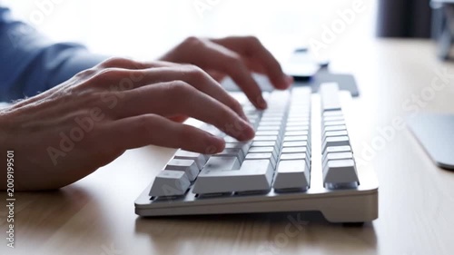 Close up of hands typing on a white computer keyboard with shallow depth of field
