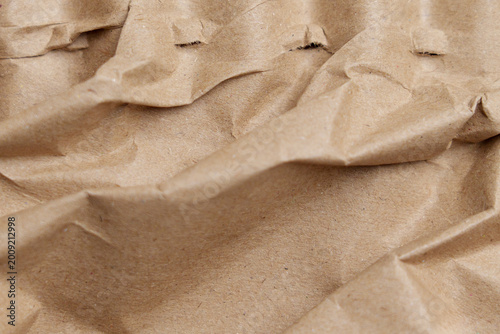 Crumpled kraft packaging paper with many folds and creases. Recycled wrapping material. Close up