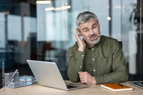 Fotografi Confused man having difficulty hearing during office workday