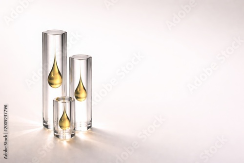 Golden Oil Droplets Suspended in Minimalist Glass Cylinders Conceptual Laboratory Still Life on White Background