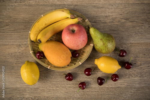 Bilde på lerret Fresh assorted fruit in bamboo basket on rustic wooden table