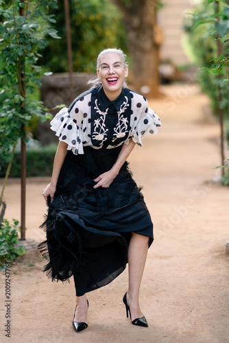 Fashionable woman showcasing joyful energy with polka dot attire on sunlit pathway