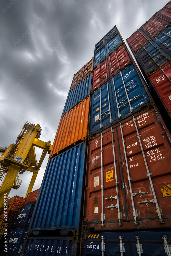 Fototapeta premium Towering stacks of shipping containers under stormy sky