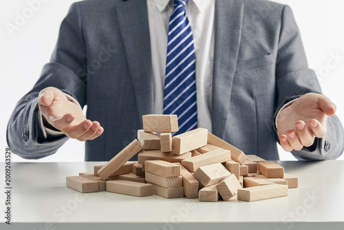 Cuadro en lienzo Businessman Behind Fallen Wooden Blocks Representing Business Collapse and Risk