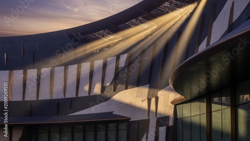 Modern architectural building with unique design and sunlight reflections at sunset