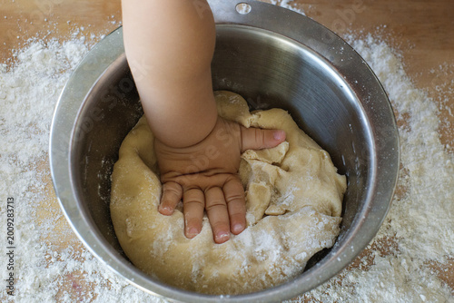 Tableau sur toile Close up of a child hand kneading dough in a metal bowl surrounded by flour