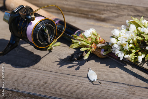 Foto A spinning rod with a reel and fishing lures lies on an old wooden table next to