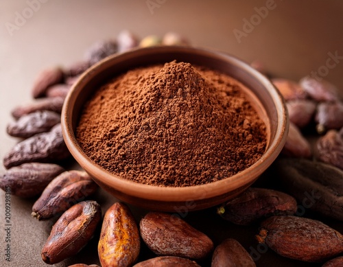 close up of cocoa powder in a brown ceramic bowl raw cocoa beans around with copy space concept of cocoa trading cocoa pricing increasing or changing food ingredient