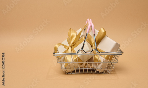 A stack of boxes tied with a golden ribbon on a beige background