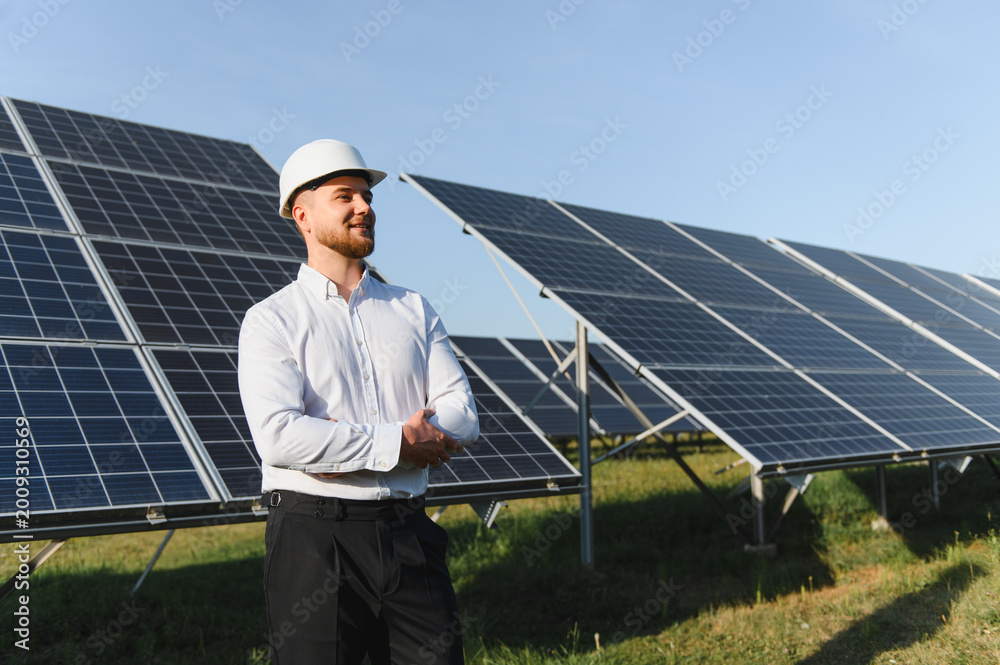Fototapeta premium Engineer in hard hat standing in solar farm