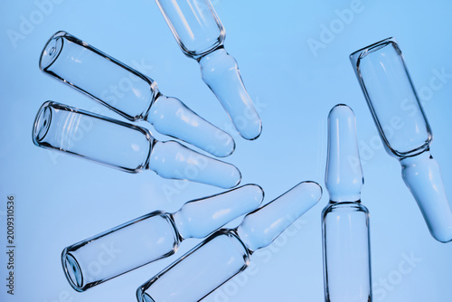 Ampoules with medicine against blue background, representing medical innovation and vaccine development