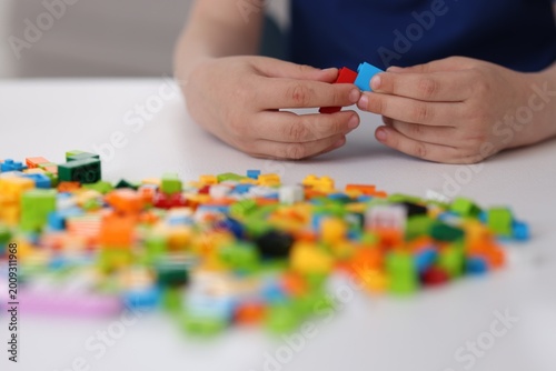 Construction toy. Little boy playing with building blocks at white table indoors, closeup