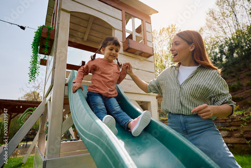 Cuadro en lienzo Carefree mother and daughter in enjoying day on playground.