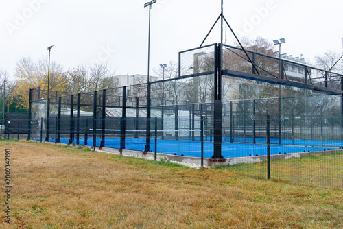 Modern outdoor padel court enclosed by glass and metal fencing