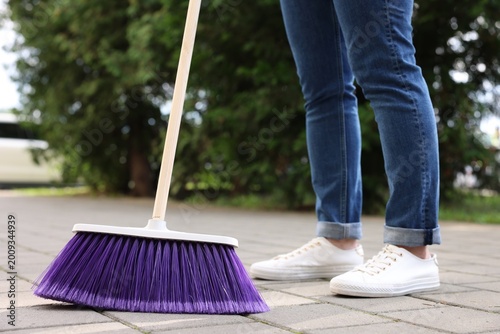 Fotografía Woman with broom sweeping pavement outdoors, closeup