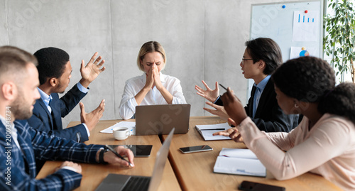 Foto Aggressive Colleagues Shouting At Unhappy Victimized Business Lady Sitting At Desk In Modern Office