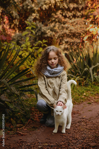 Happy little child girl with cat. Portrait of kid with pet.