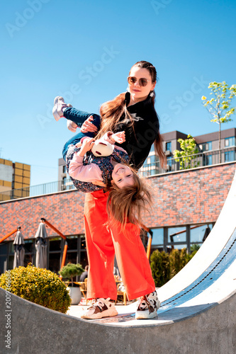 Schilderij op canvas Young mother holding her daughter upside down and having fun outdoors