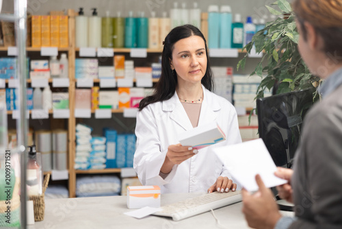 Fotografia Female pharmacist giving prescription medicine to male buyer at pharmacy