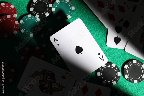 Casino chips and playing cards on green table, flat lay