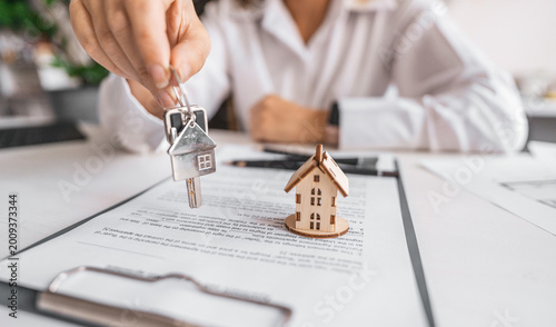 Photos Woman real estate agent gives keys paperwork and miniature house model