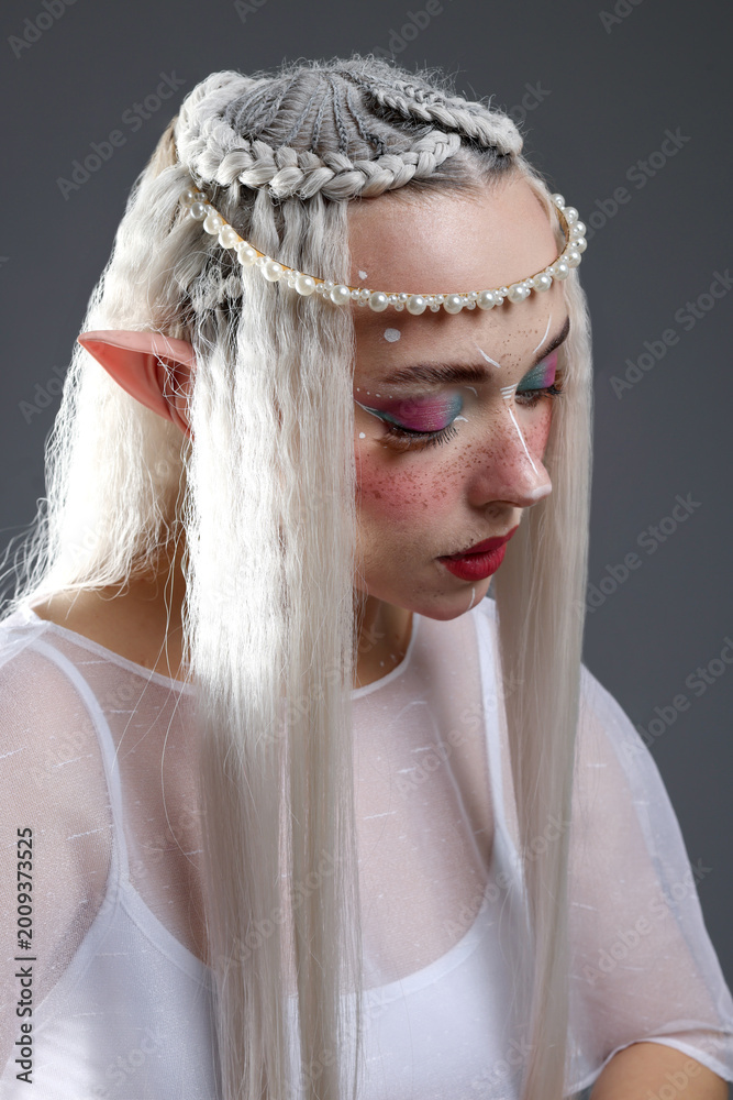 Fototapeta premium Beautiful girl dressed as elf on grey background