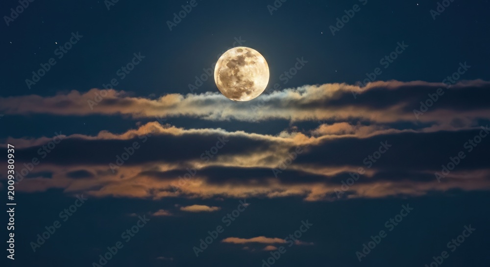 Fototapeta premium Night sky with a bright full moon partially obscured by colorful clouds