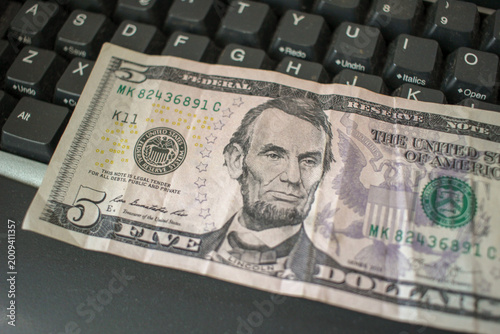 Five dollar bill on computer keyboard for technology cost and online payment concept