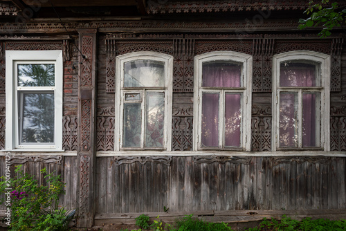 Photos The windows and the wall of a wooden house decorated with carved patterns