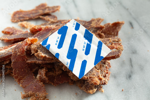 A view of a silica gel packet on a pile of steak jerky.