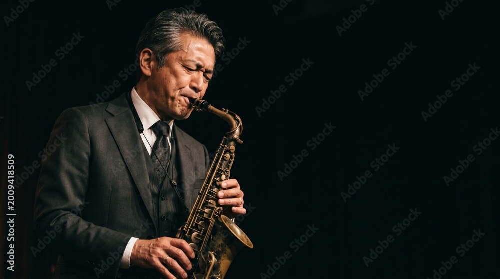 Naklejka premium 漆黒の静寂と情熱。緊張感溢れる日本人男性ジャズアーティストのプロフェッショナルなポートレート