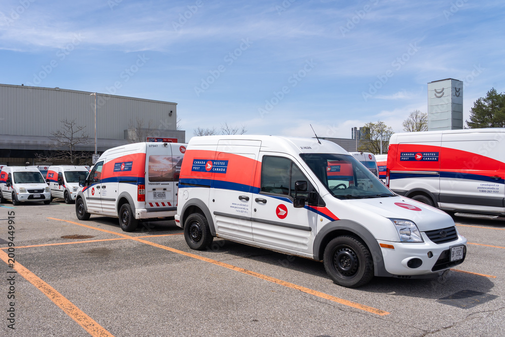 Naklejka premium Toronto, Canada - April 26, 2026: Canada Post delivery vehicles parked in a parking lot at a Post office in Toronto, Canada. Canada Post is a Crown corporation owned by the federal government.