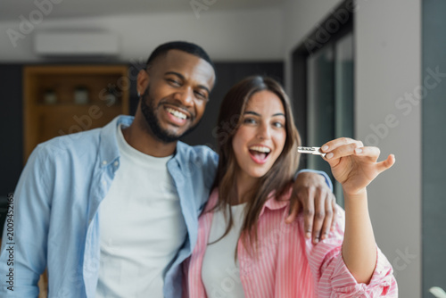Photos Happy young couple celebrates receiving keys to their new apartment, smiling and embracing in a modern interior