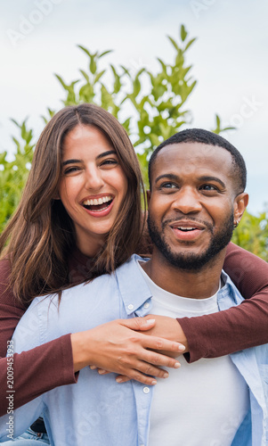 Photos Happy young couple share a joyful embrace outdoors, laughing together in a casual romantic portrait that conveys love, connection, friendship and carefree moments in a natural garden setting