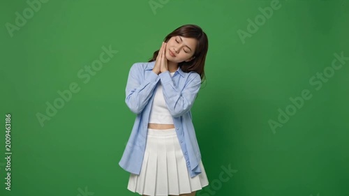 Young woman shows sleep symbol on green screen