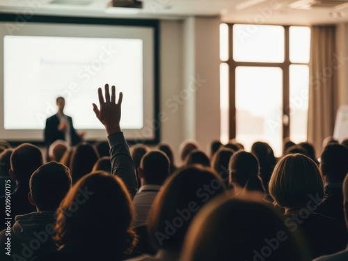 Person raising hand in a lecture hall audience