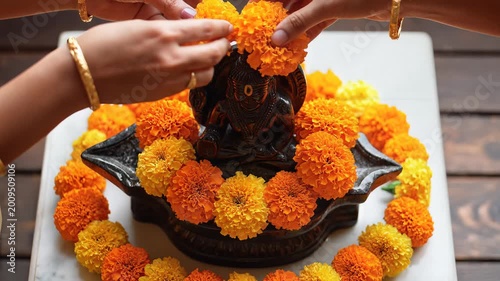Devotees offering marigold flowers to Shani Dev statue for puja