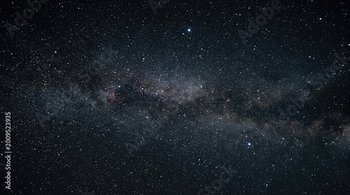 Dense starfield and Milky Way band stretch across deep space on dark night sky.