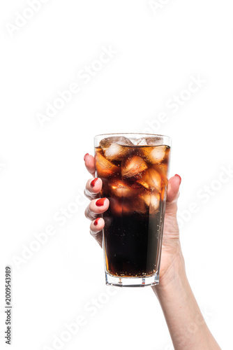Glass of soda drink with ice in female hand isolated on white background